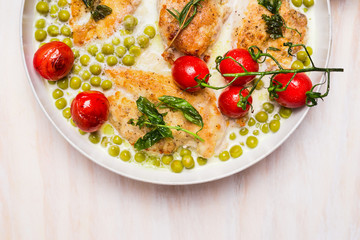 Cooking pan with chicken breast , green pea and roast tomatoes