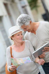 Senior tourists walking in street with map and tablet