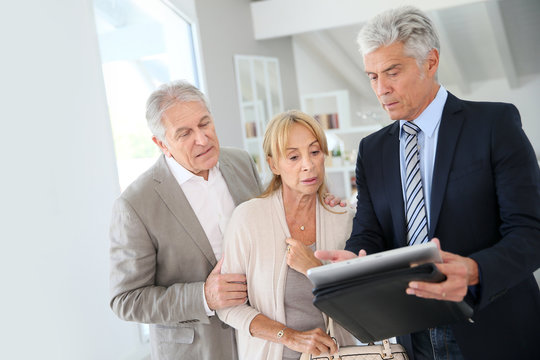 Senior couple with real-estate agent visiting house for sale