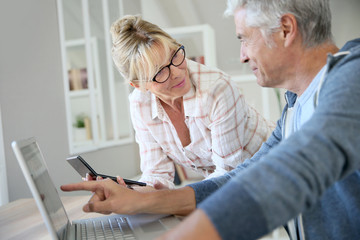 Senior couple at home checking expenses on internet