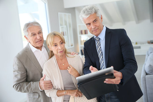 Senior couple with real-estate agent visiting house for sale