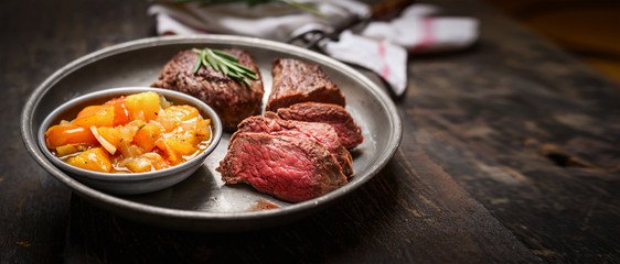 Slices of medium rare roasted meat steak and salsa sauce