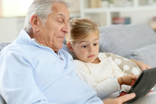 Little girl with grandpa playing with digital tablet