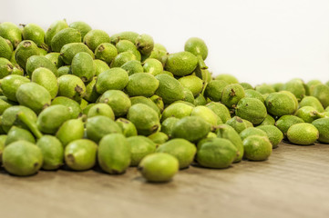 A lot young green walnuts in husks on brown wooden kitchen table