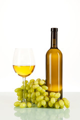 Fototapeta premium Weißwein im Glas und in der Flasche mit Weintrauben