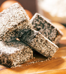 Group of Lamingtons on a timber cutting board with food ingredients in the background 