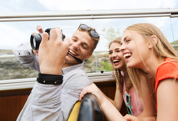 happy friends with camera traveling by tour bus