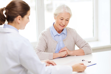 Obraz premium doctor with clipboard and senior woman at hospital