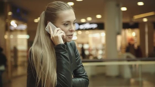 Beautiful girl with long hair, talking on the phone in the mall