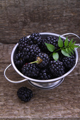 blackberries in a metal bowl on the old wooden background