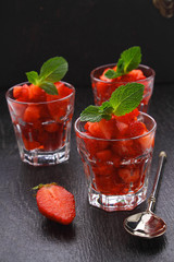 dessert of strawberries decorated with mint leaves on a black background