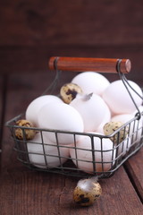 white chicken and brown quail eggs in a basket