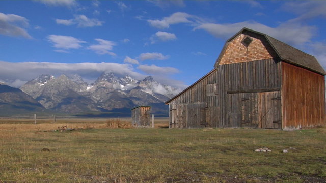 An old barn rises out of a prairie with the Grand Tetons in the background.