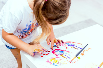 Obraz na płótnie Canvas Little beautiful girl draws paints.