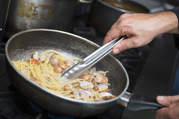 chef is cooking spaghetti alla vongole