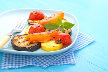 grilled vegetables (zucchini, peppers, tomatoes) on a blue plate