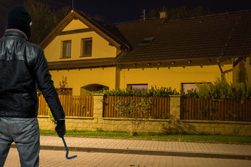 Masked thief in balaclava is going to steal and rob the house at