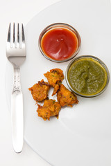 pakora an indian breakfast both vegetarian as well as non vegetarian deep fried served with sauce and green chutney available with clipping path