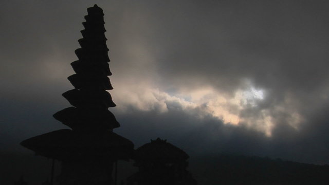 Part of a Balinese temple stands in silhouette.