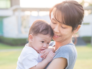  Portraiture of Asian mother and baby in bright sunlight outdoor.