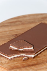 Broken brown white chocolate on the wooden board