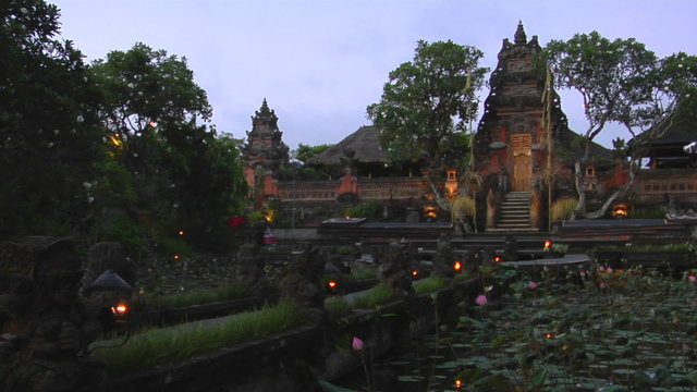 A beautiful Balinese temple has a pond of lily pads in front.