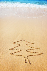 Christmas tree drawn in sand at the beach