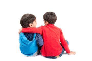 Little sibling boys sit together on white background