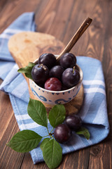 Plums with napkin on wooden table