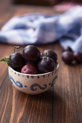 Plums with napkin on wooden table