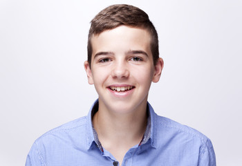 Portrait of a teenager boy smiling on gray background