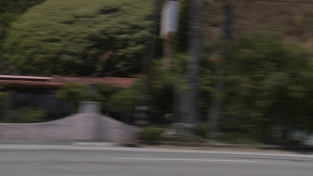 A car travels along Pacific Coast Highway as seen through the side window.