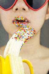 Beautiful woman with red lolita sunglasses sexy eating banana. Studio shot