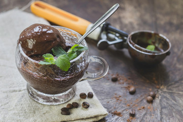 Homemade chocolate ice cream with banana and peanut butter,  in a glass bowl on a wooden table. Selective focus