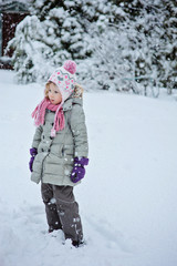 Fototapeta na wymiar child girl in grey coat on the walk in snowy winter garden