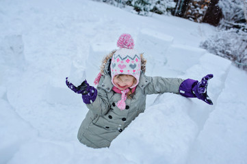 Fototapeta na wymiar happy child girl playing snowballs in snow castle in winter garden