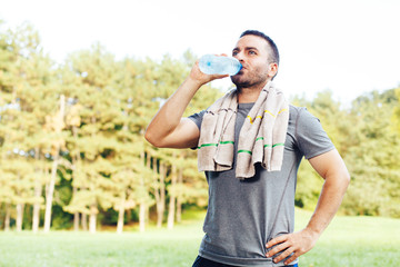 Naklejka premium Young man drinking water from a bottle after workout
