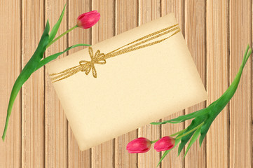 Pink tulips and greeting card over shabby yellow wooden table