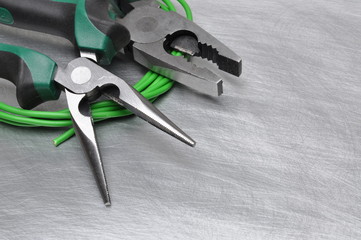 Green electrical tools and cables on metal surface with place for text 