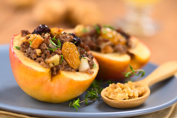 Savory baked apple filled with mincemeat, raisins, sultanas, onion, walnut, sprinkled with fresh thyme leaves (Selective Focus, Focus on sultana in front)
