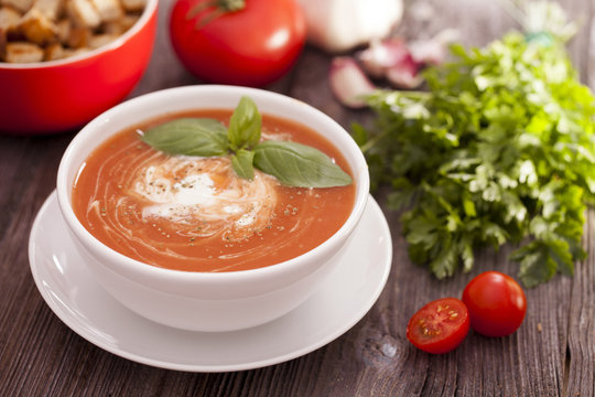 Delicious tomato soup with aromatic spices on a wooden table.