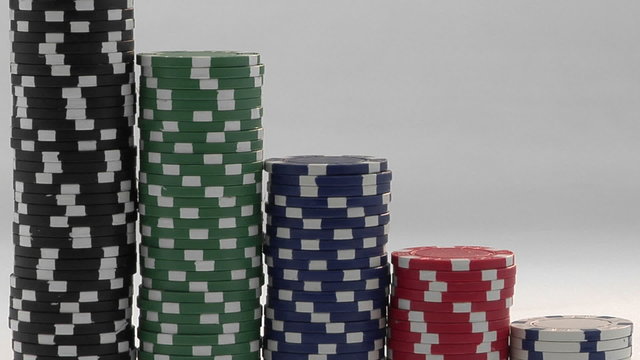 Stacks of poker chips sit in a row, arranged by value.