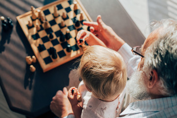 Grandfather teaches his grandson to play chess