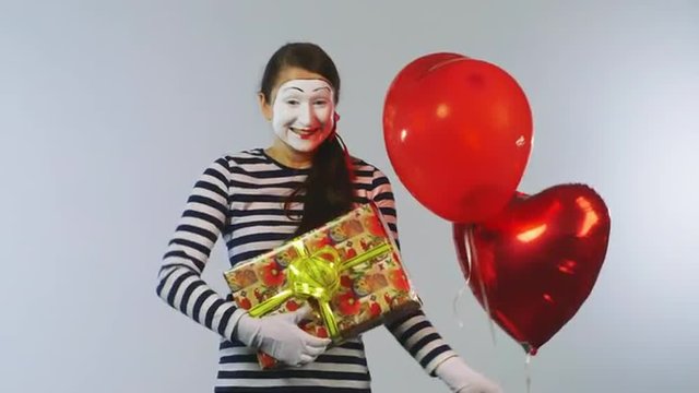 Cheerful girl mime with balls and gifts. Concept: Holidays