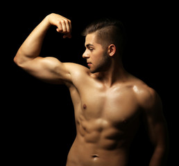 Obraz na płótnie Canvas Muscle young man on dark background