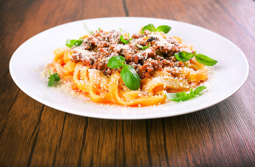 Pasta Bolognese with parmesan and basil on table close up