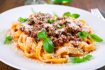 Pasta Bolognese with parmesan and basil on table close up