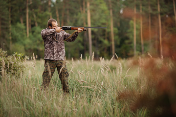 Fototapeta premium Young male hunter in camouflage clothes ready to hunt with hunt