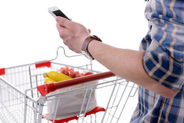 Young man holding mobile phone and shopping cart isolated on white