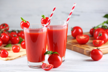 Glasses of tomato juice with vegetables on wooden table close up